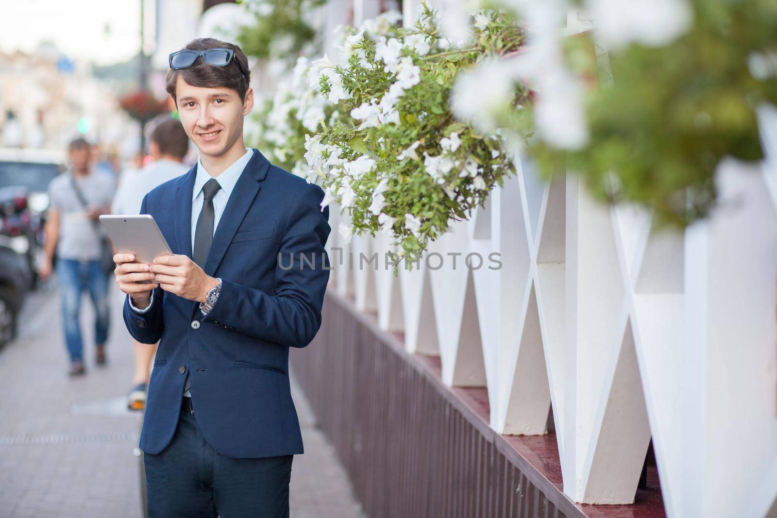 young man in business suit holding tablet on summertime day.