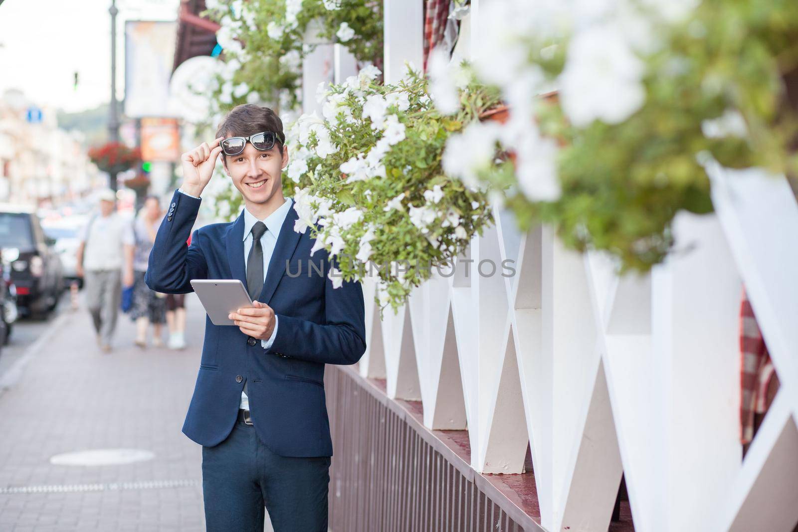 young man in business suit holding tablet on summertime day.