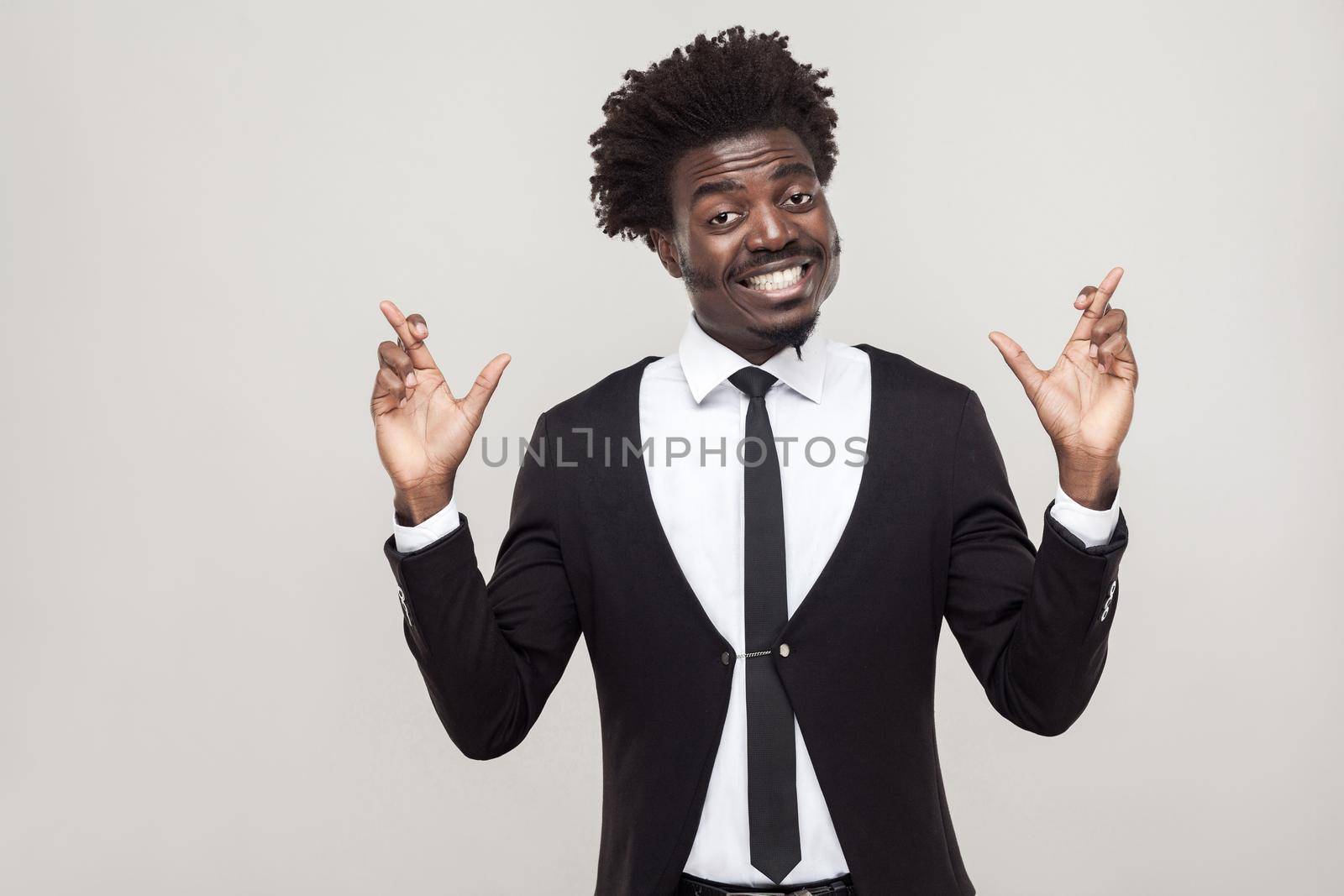 Happiness man wish and pray. Showing good luck sign. Studio shot, isolated on gray background