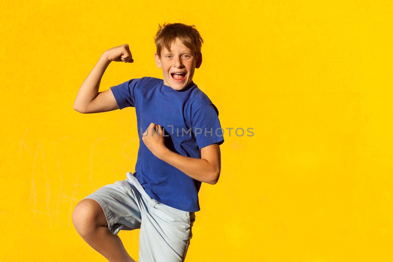 Funny an happiness freckles boy in summer. Indoor, studio shot. Yellow background
