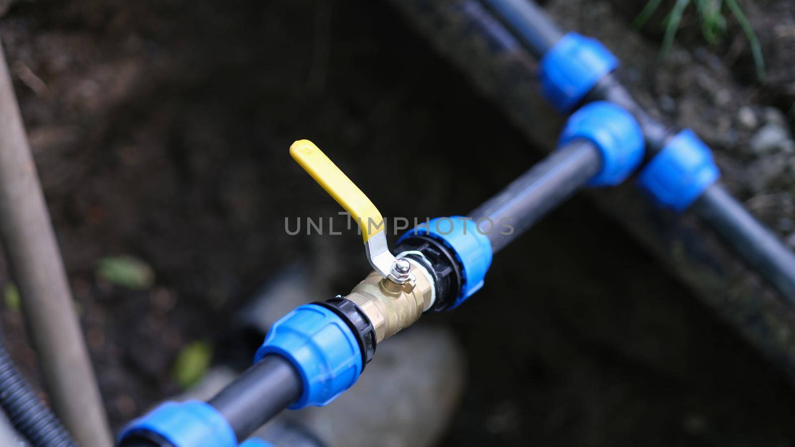 Water valve connected to PVC pipe closeup by kuprevich