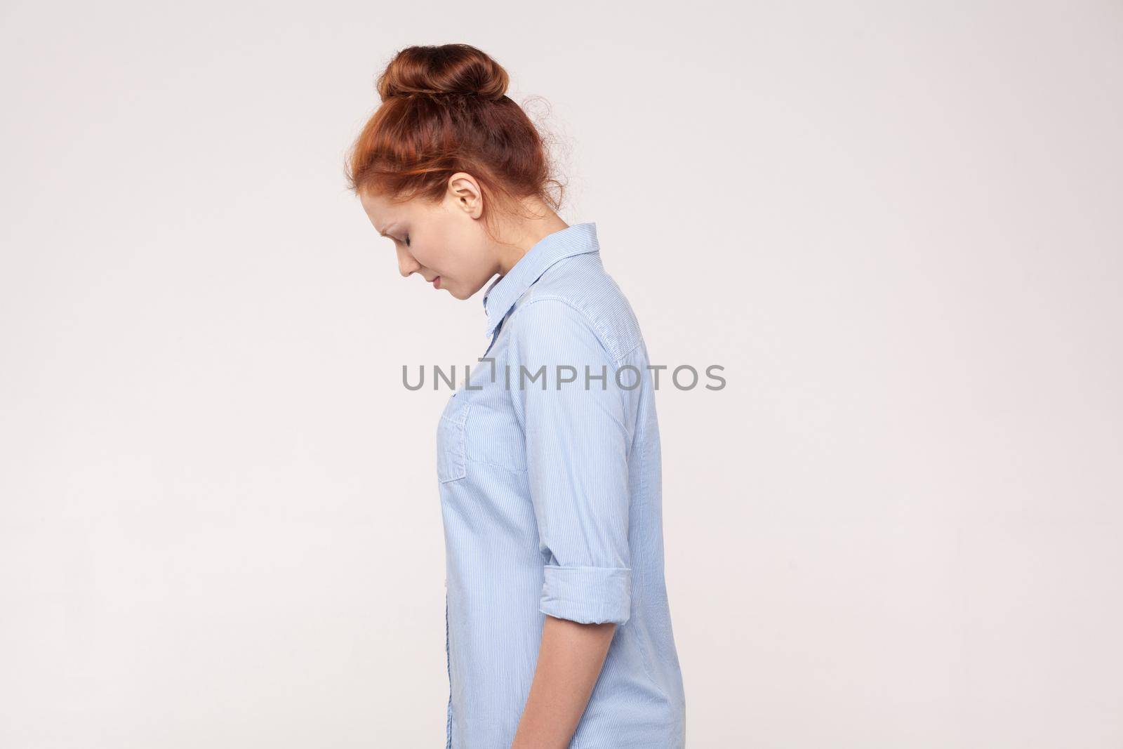 Side view, profile sad red head businesswoman. Isolated on gray background. Studio shot