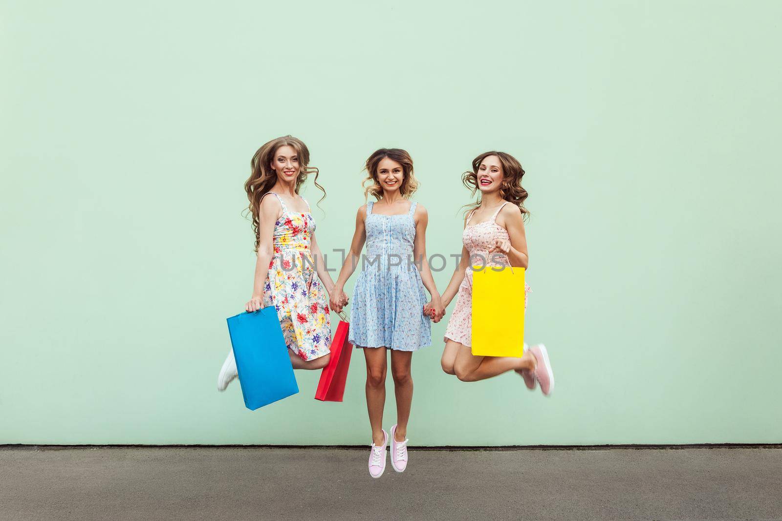 Happiness beautiful three friends jumping from happy with colorful packets after shopping. by Khosro1