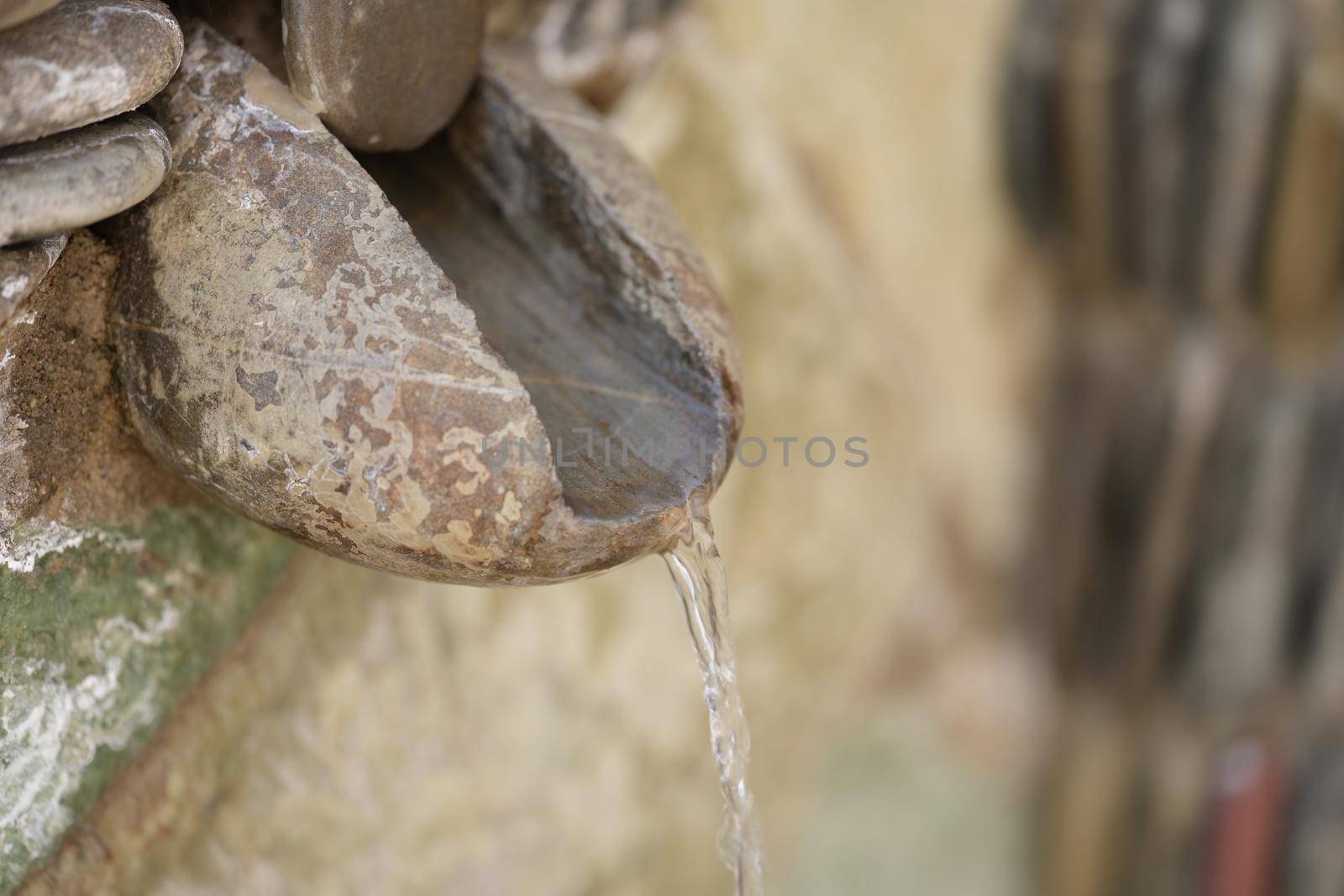 Old stone and fountain with spring water flowing into pool. Antique water pipe made of stones concept