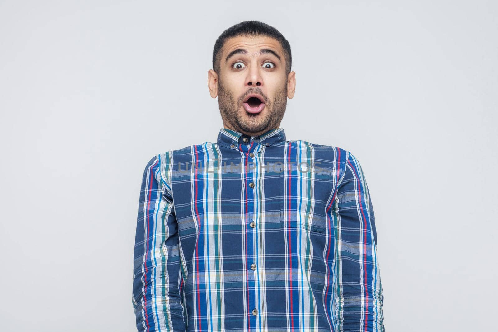 Wondered business man. Looking at camera with shocked face and big eyes and open mouth. Isolated on gray background, studio shot. Indoor