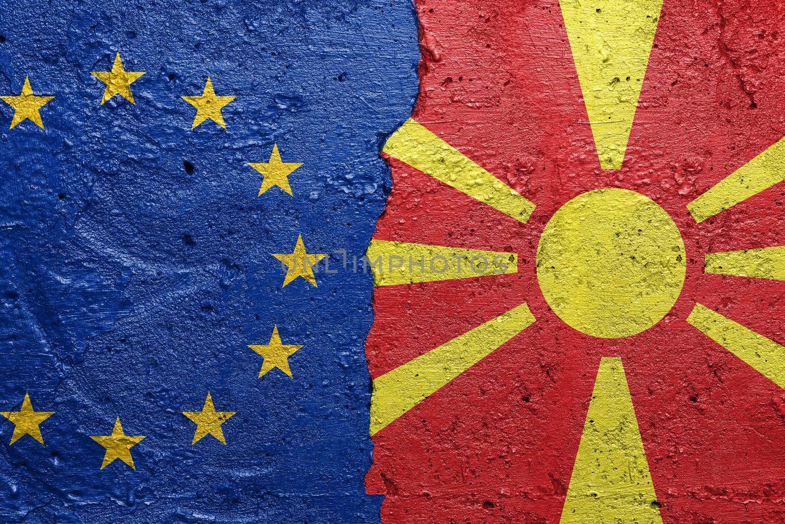 European Union and North Macedonia - Cracked concrete wall painted with a EU flag on the left and a Macedonian flag on the right stock photo by adamr