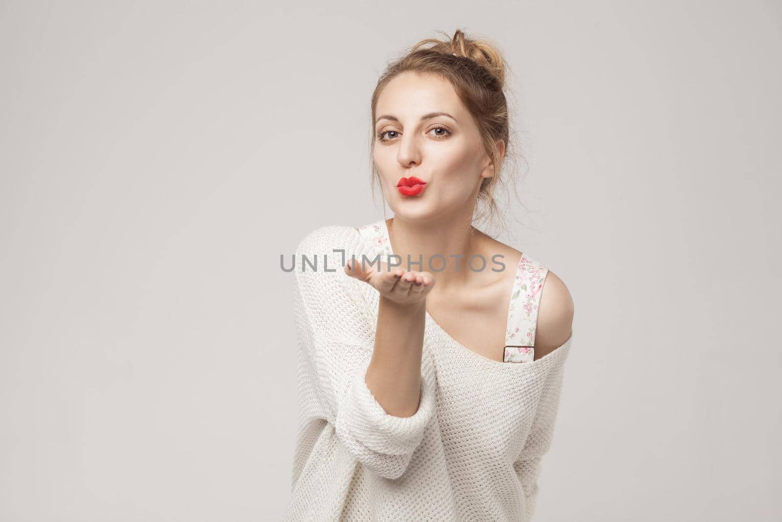 Romantic woman send air kiss at camera. Studio shot, isolated on gray background