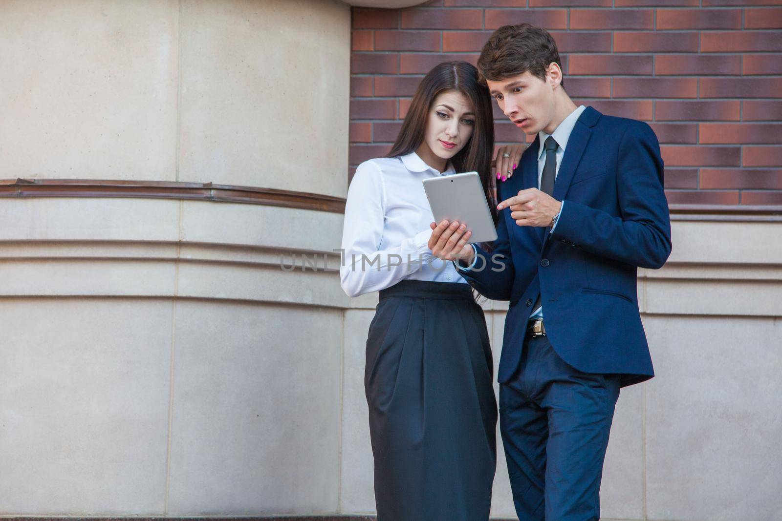 Business people using a digital tablet outdoor. Businessman and Businesswoman standing friendly on steps and using tablet with smile in the city.