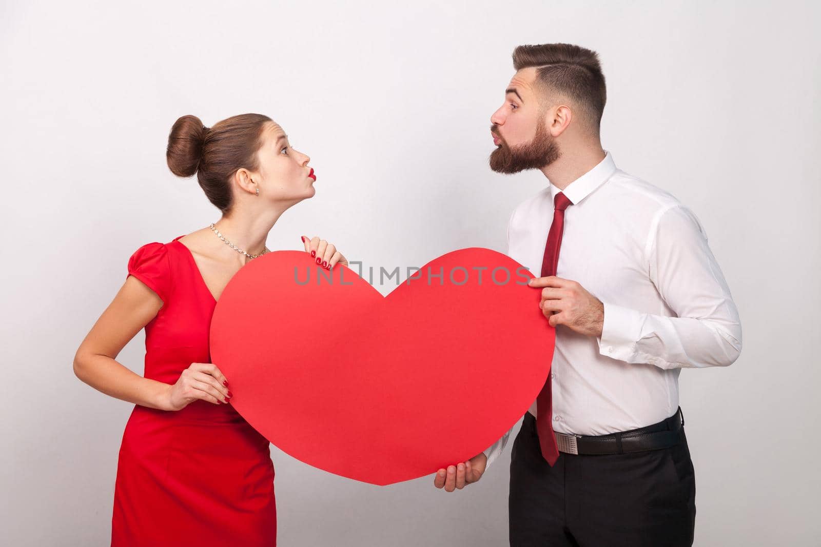 Family celebrate valentine's day, sending each other air kiss. Indoor, studio shot, isolated on gray background