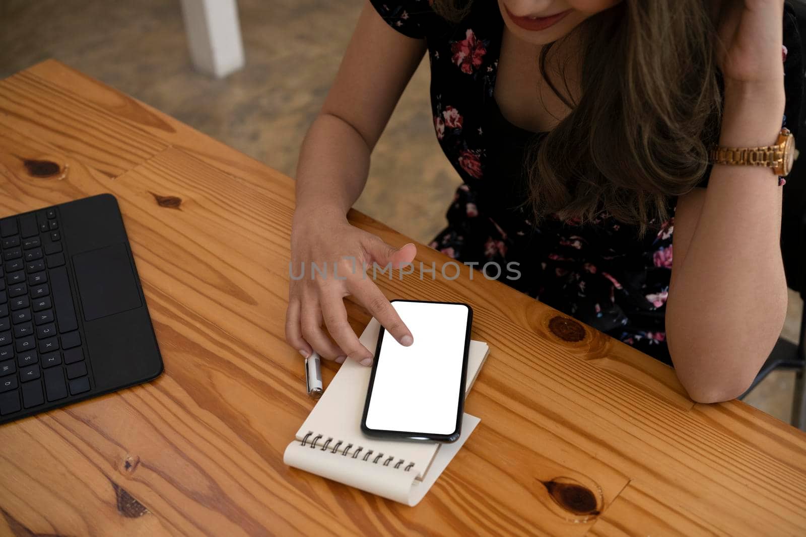 Young female office worker sitting in office and using smart phone.