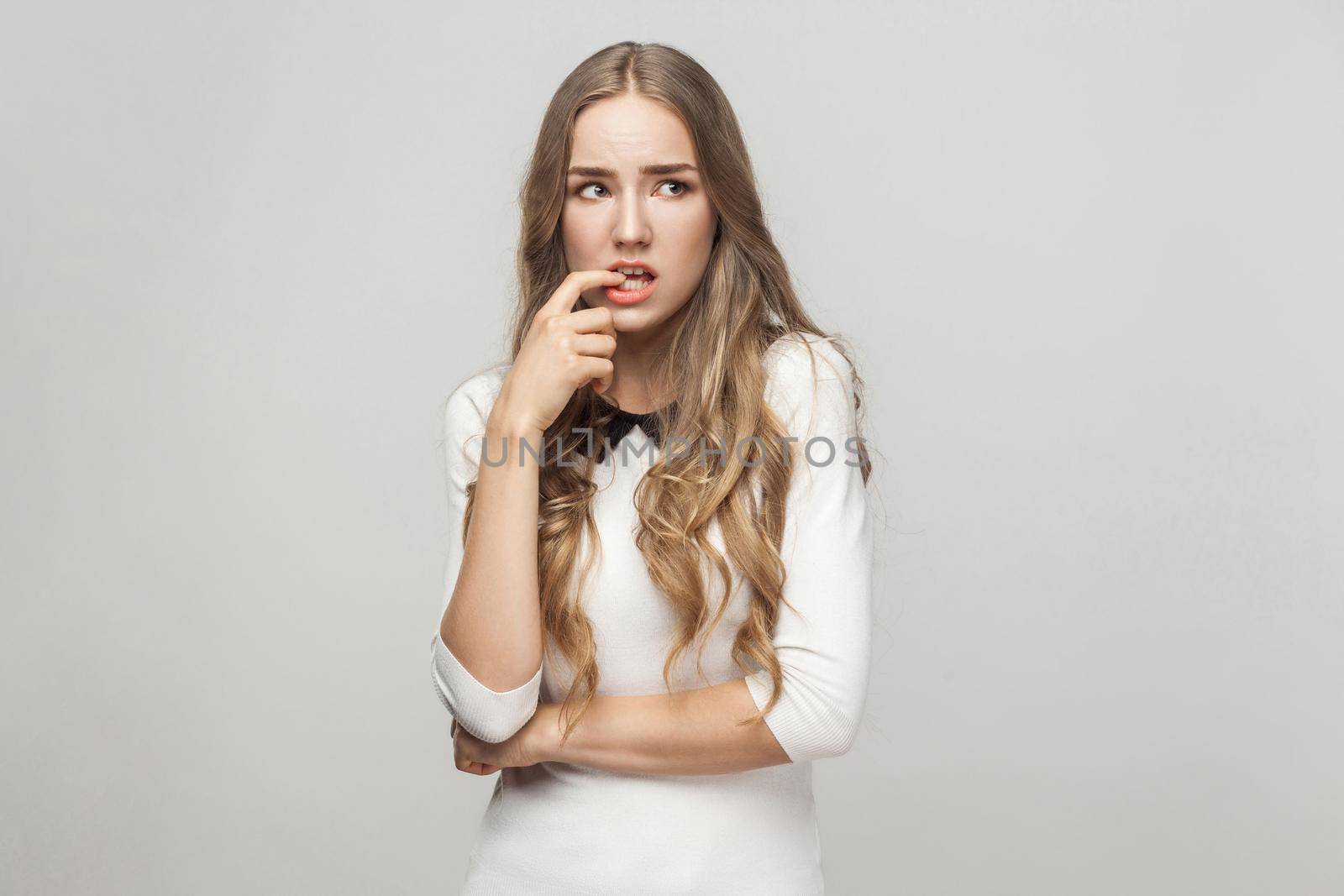 Hmm, let's my think. Confusion beautiful woman touching fingers her chin and wondering. Studio shot, gray background