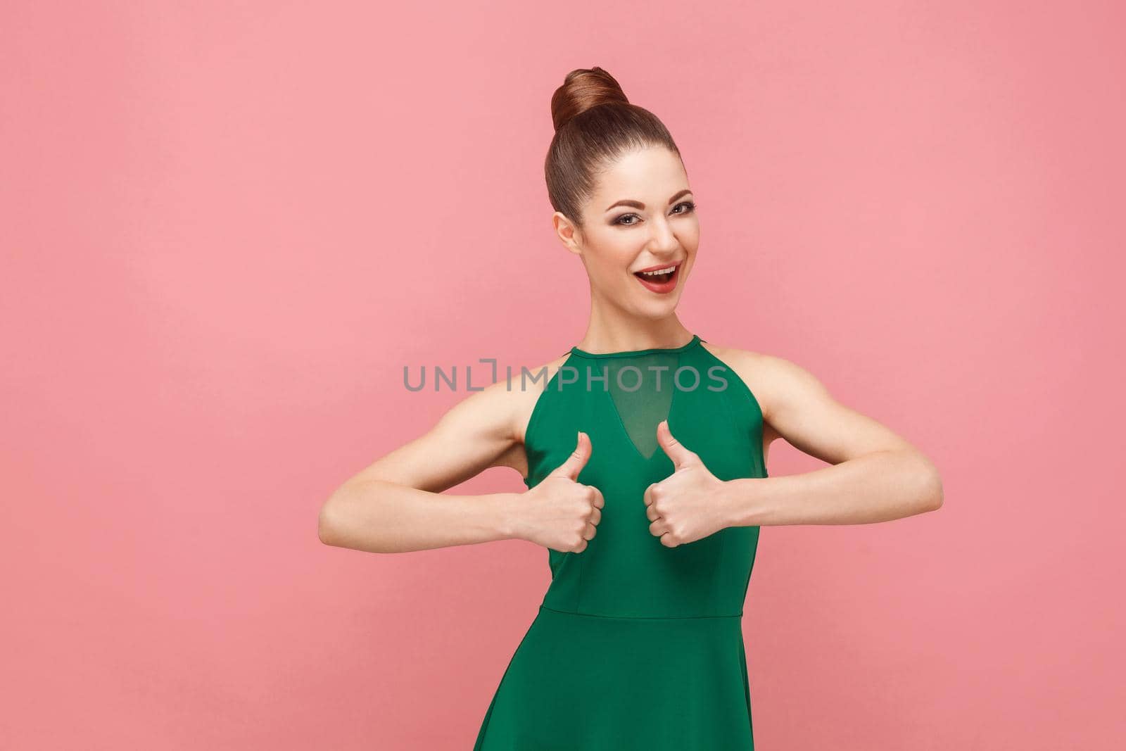 Cute woman showing like sign, thumbs up. Expression emotion and feelings concept. Studio shot, isolated on pink background