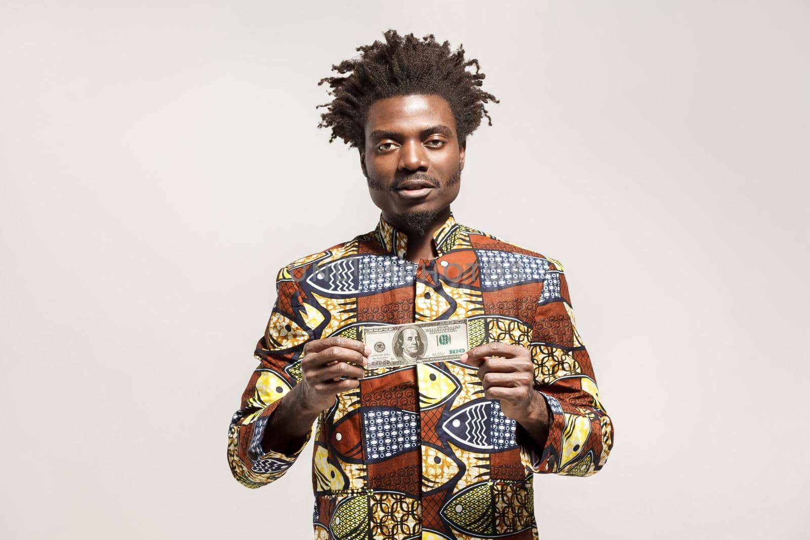 Kongo businessman holding one dollar and looking at camera. Indoor, isolated on gray background