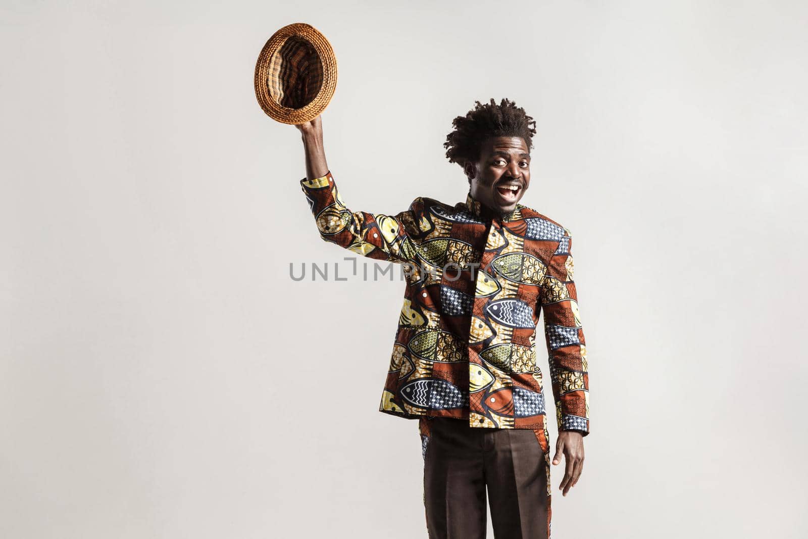 Crazy and funny african man toothy smiling , looking at camera. Indoor, isolated on gray background