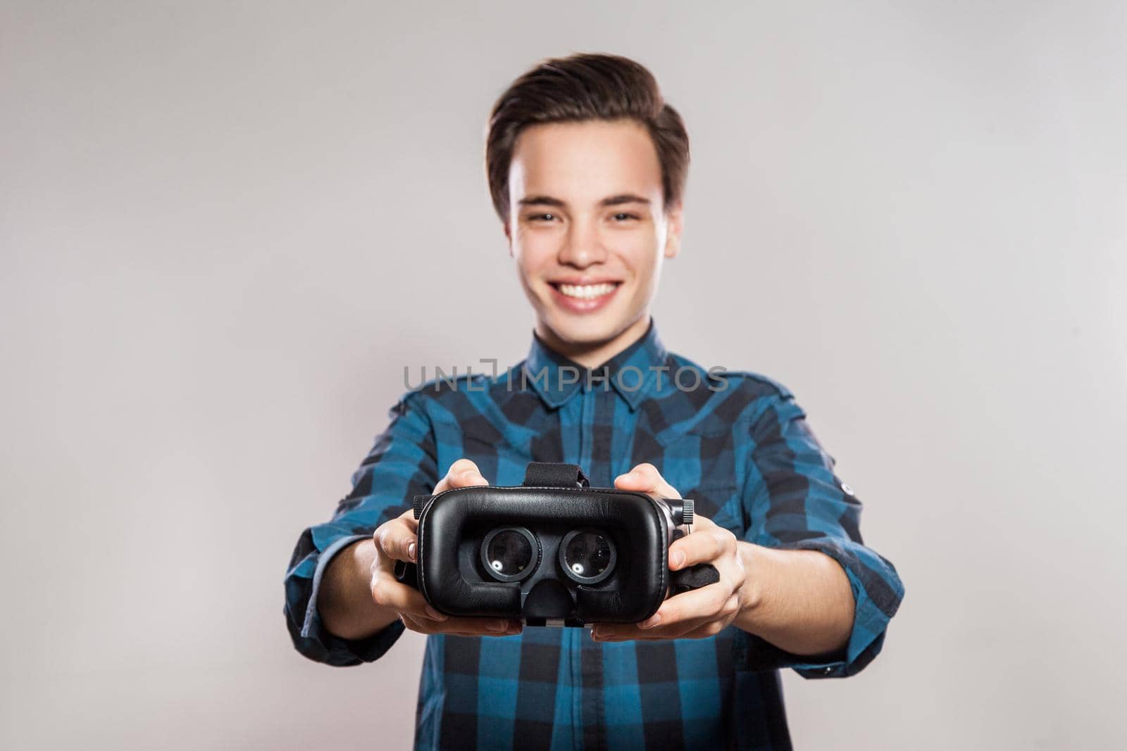 Portrait of young man with virtual reality headset. indoor, isolated on gray background.