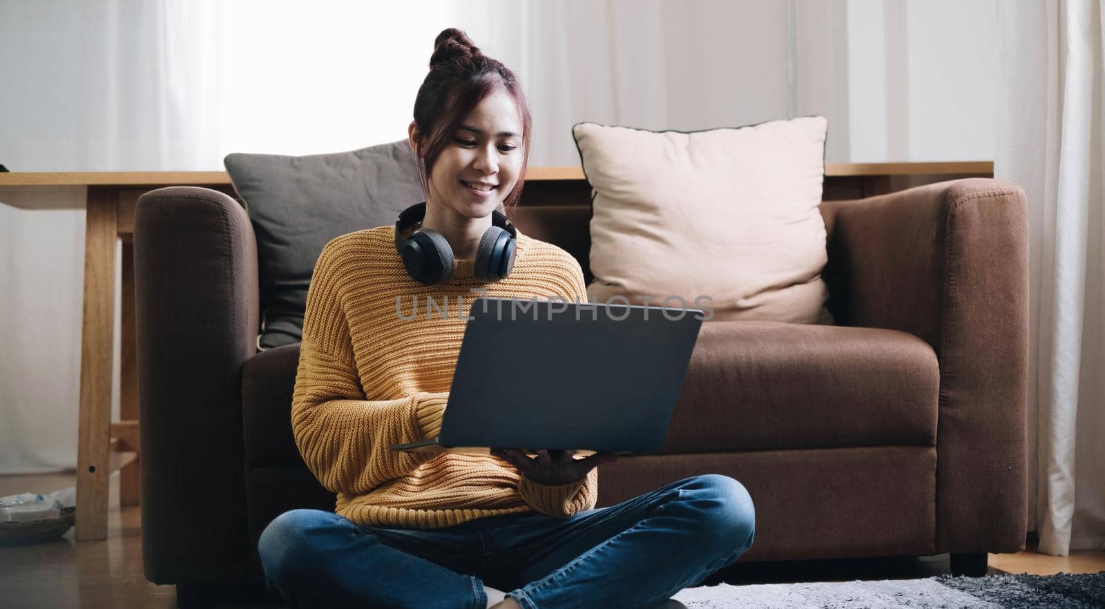 Shot of pretty young woman using her laptop while sitting on the floor at home. by wichayada