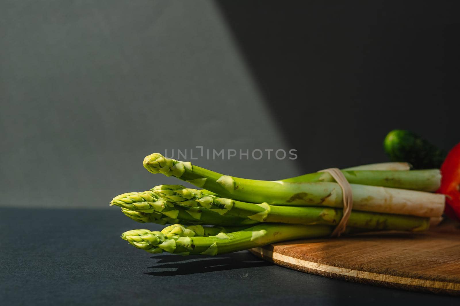 branches of fresh green asparagus on a wooden board, dark gray background, top view. Basic trend concept with copy space