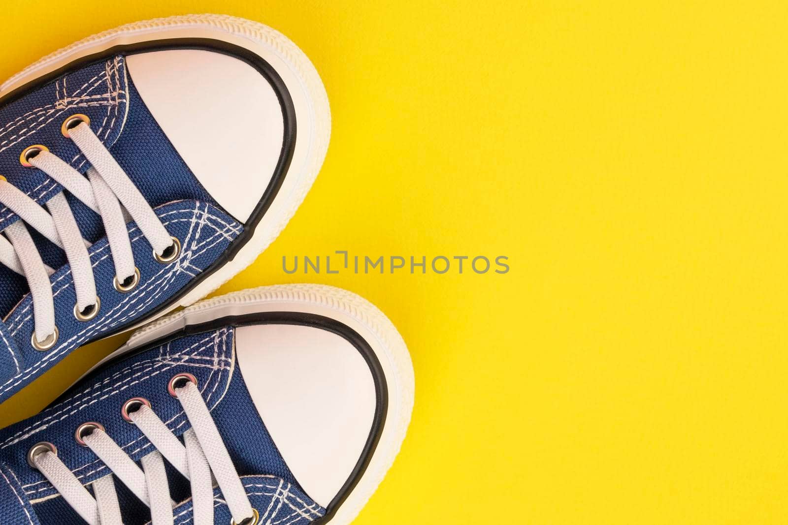 a pair of blue sneakers on a yellow background. Classic sports shoes. Fashionable youth shoes. view from above. copy space