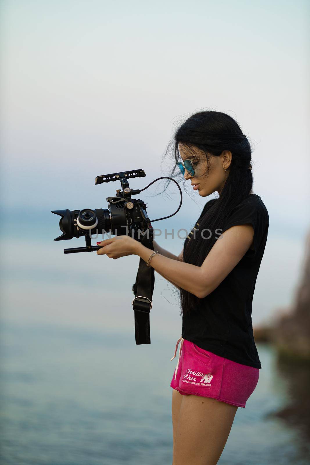 Female videographer filming a seascape with a professional movie camera by but_photo