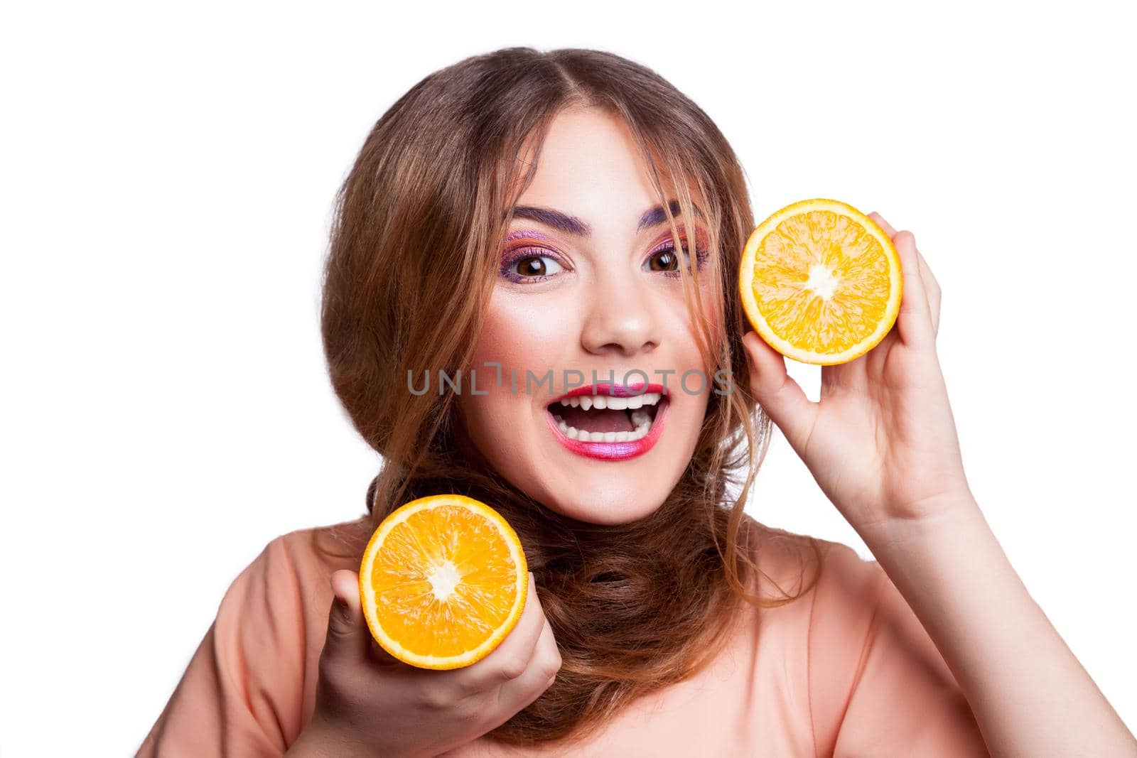 Young beautiful funny girl with orange slice and makeup and hairstyle looking at camera. studio shot, isolated on white background. .