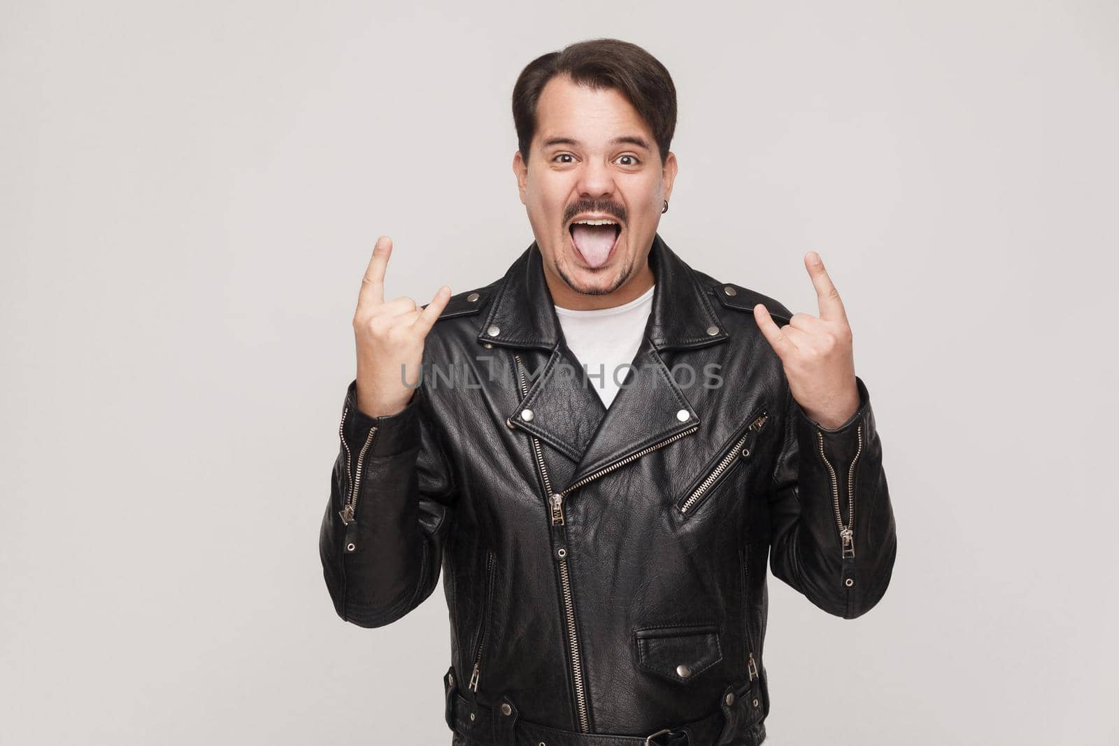 Rock and roll baby! Happines adult man toothy smiling with big eyes and showing rock sign. Indoor shot