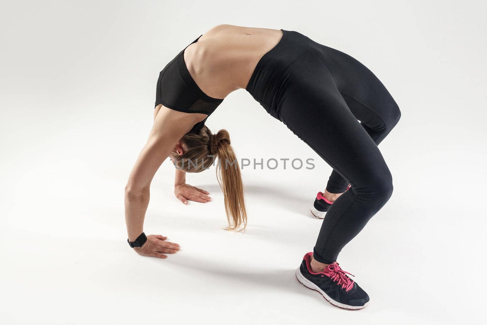 Woman have elastic spine. Bridge pose. Athletic woman doing yoga. Studio shot, gray backlground