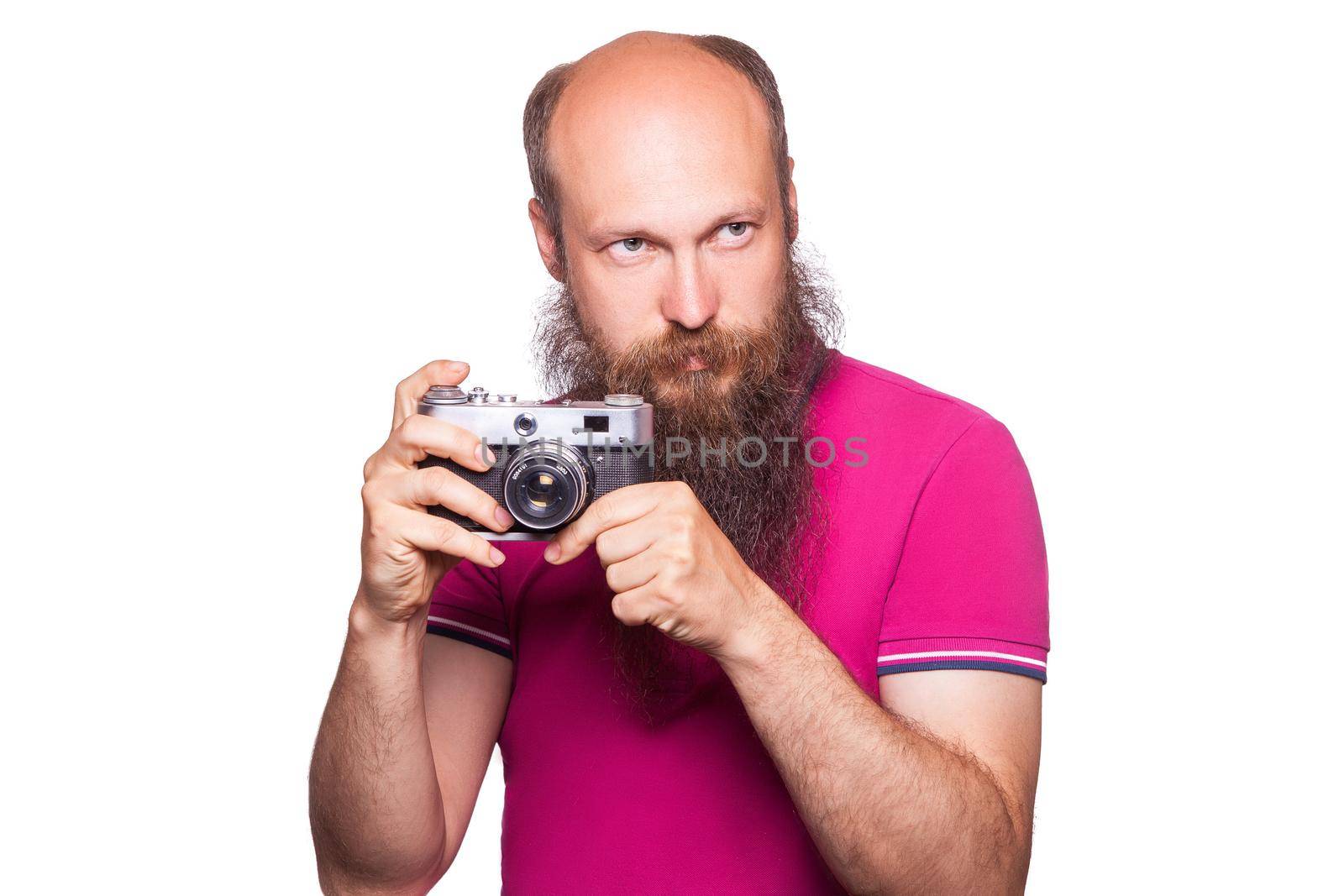 The portrait of bald bearded man photographer with pink t shirt holding classic camera. isolated on white background. studio shot.