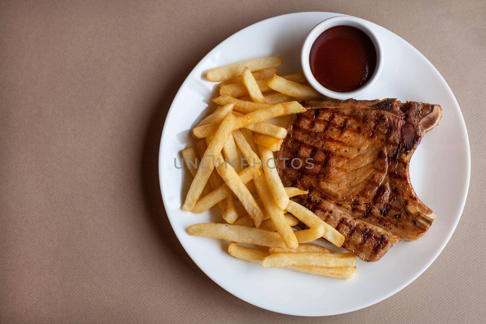 On a white plate chop grilled with French fries. by Jyliana