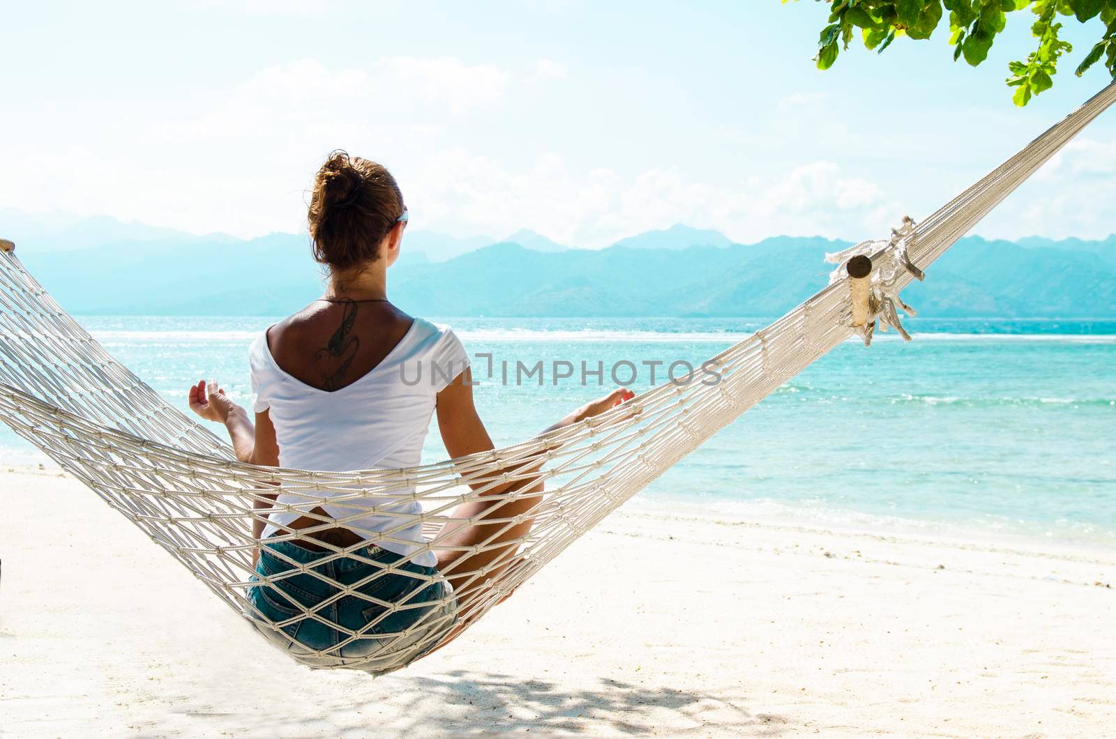 Girl meditates on a swing at the beach. Stock image.
