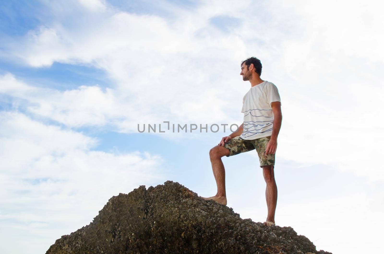 Male backpacker standing on the top by Jyliana