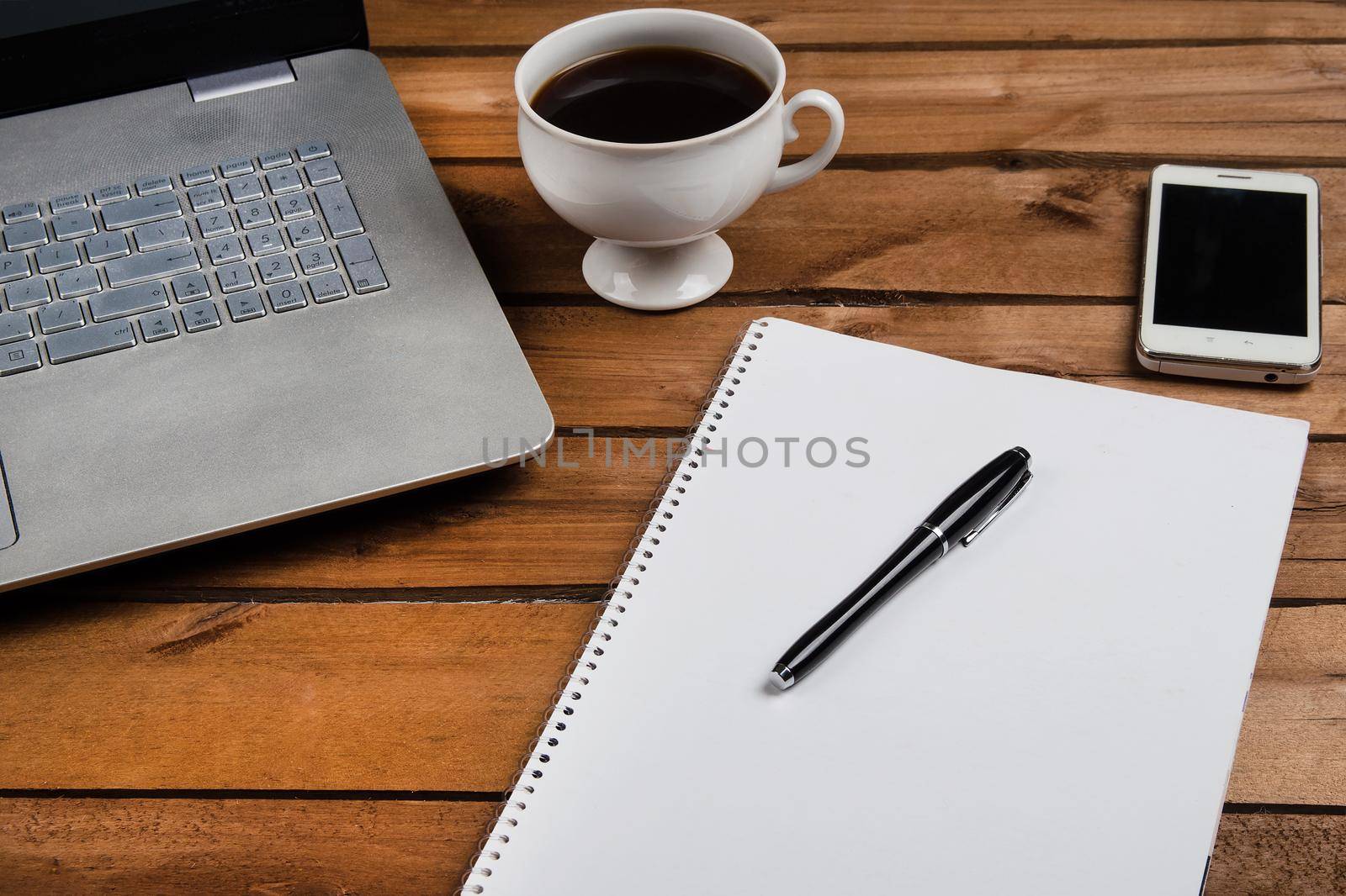 Cup of coffee and laptop on wooden table. Stock image.