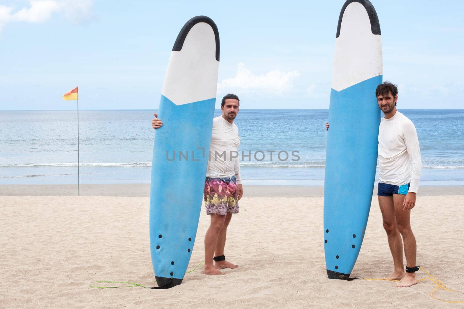 Two surfers communicating on the beach. Stock image.