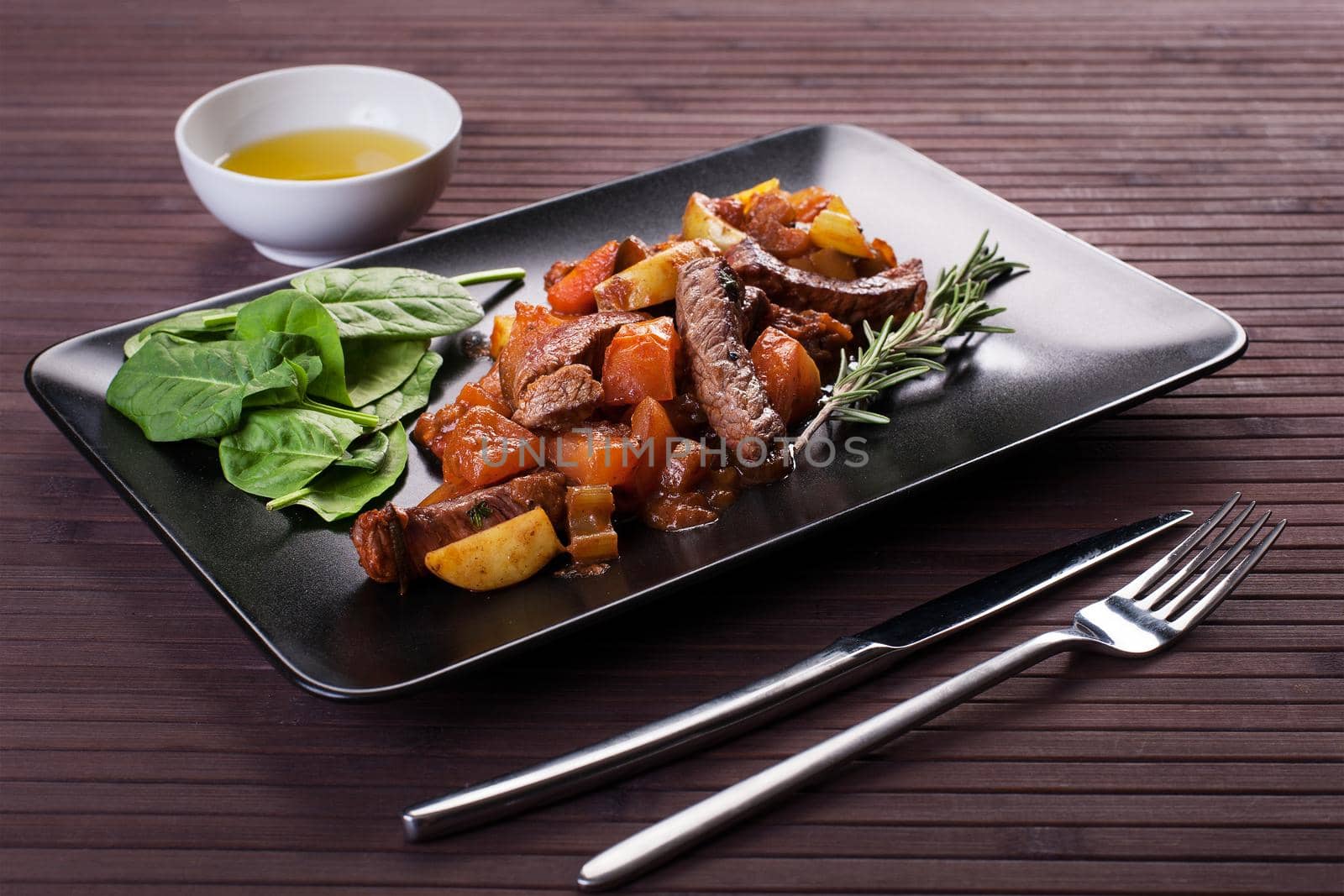 Braised veal with eggplant and other vegetables Black plate. Stock image.