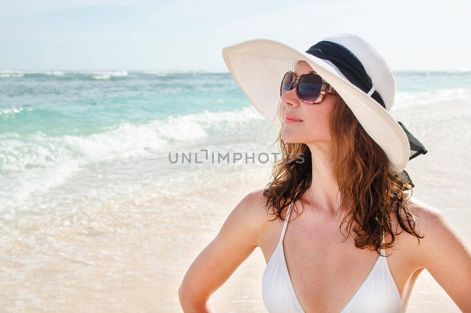 Young woman in a hat walking on the azure beach Bali. Stock image.