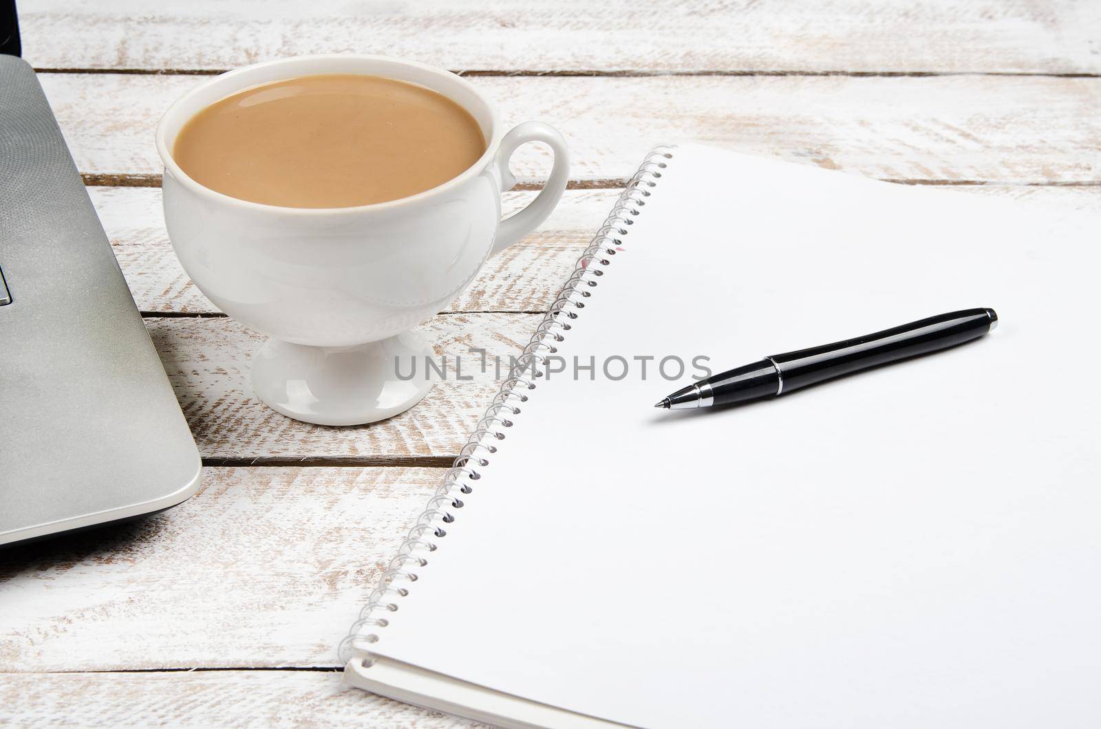 Cup of coffee and laptop on wooden office table. Stock image.