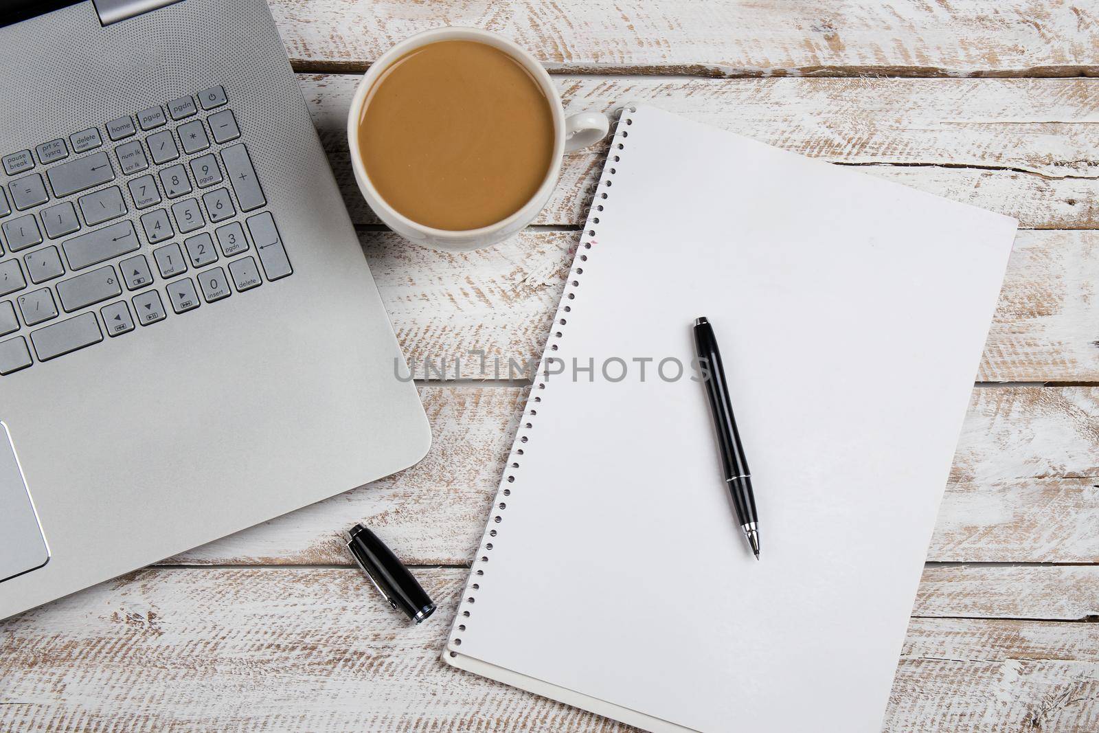 Cup of coffee and laptop on wooden office table. Stock image.