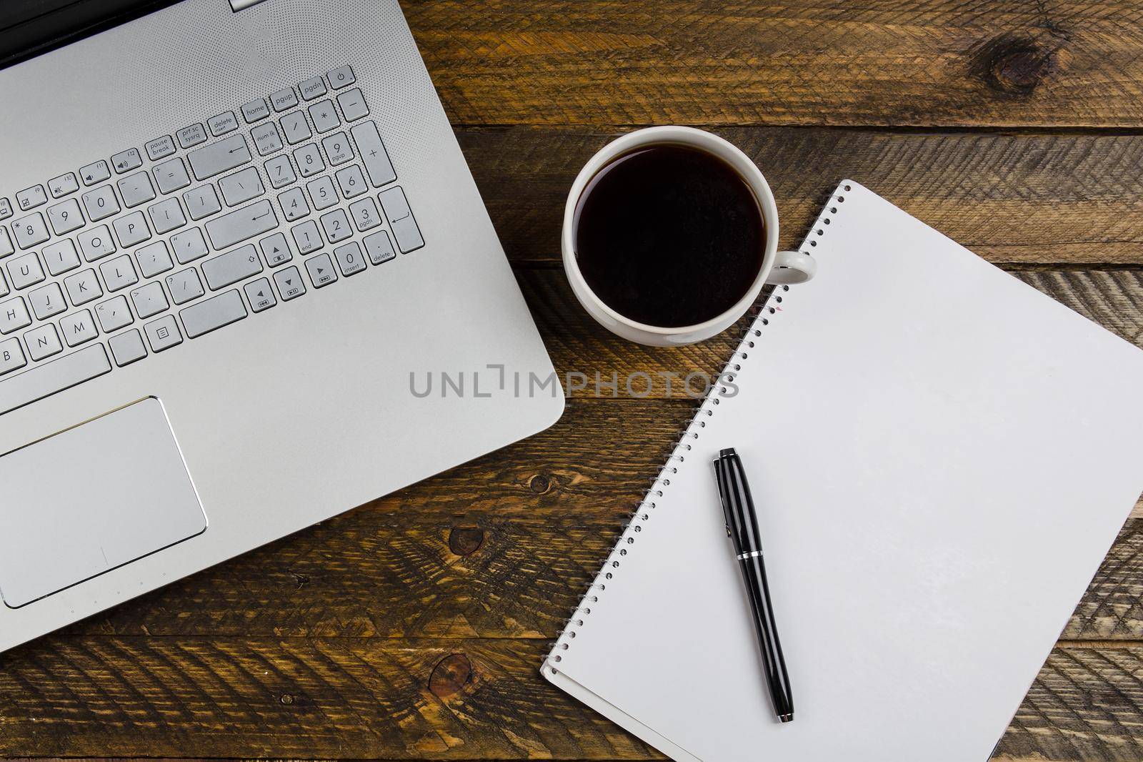 Cup of coffee and laptop on wooden table. Stock image.