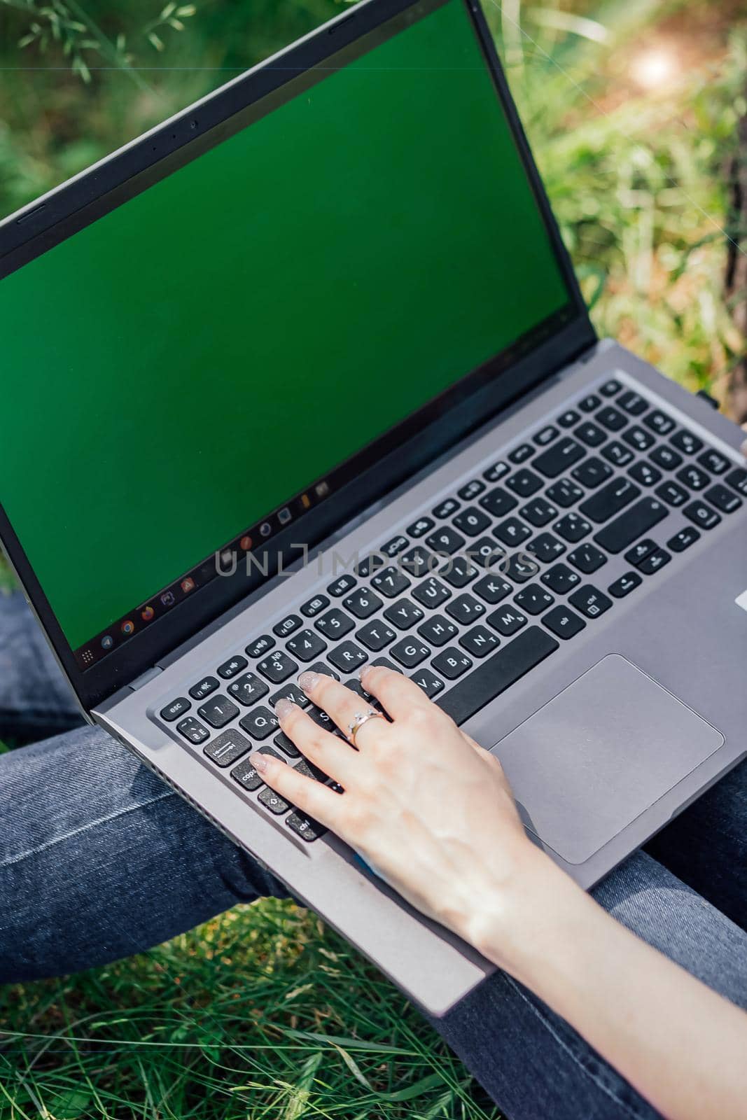 girl sits on the grass and works at a laptop. freelance. selfeducation. the concept of distance learning outdoors. by Anyatachka