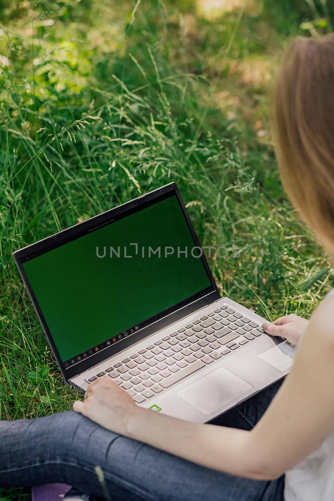 girl sits on the grass and works at a laptop. freelance. selfeducation. the concept of distance learning outdoors