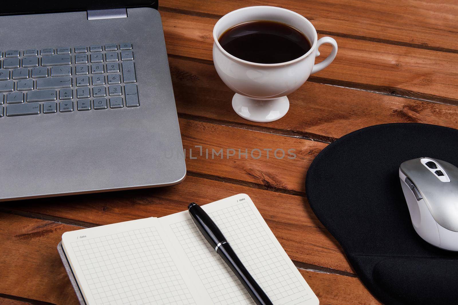 Cup of coffee and laptop on wooden table. Stock image.