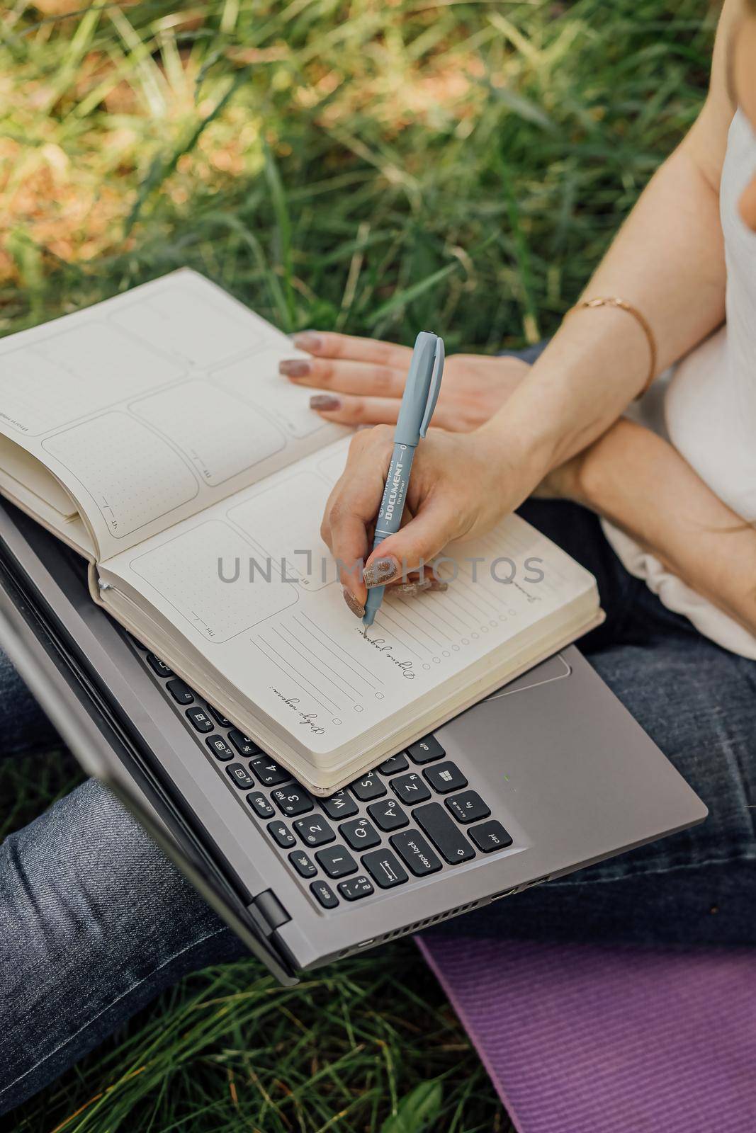 girl sits on the grass and works at a laptop. freelance. selfeducation. the concept of distance learning outdoors. by Anyatachka