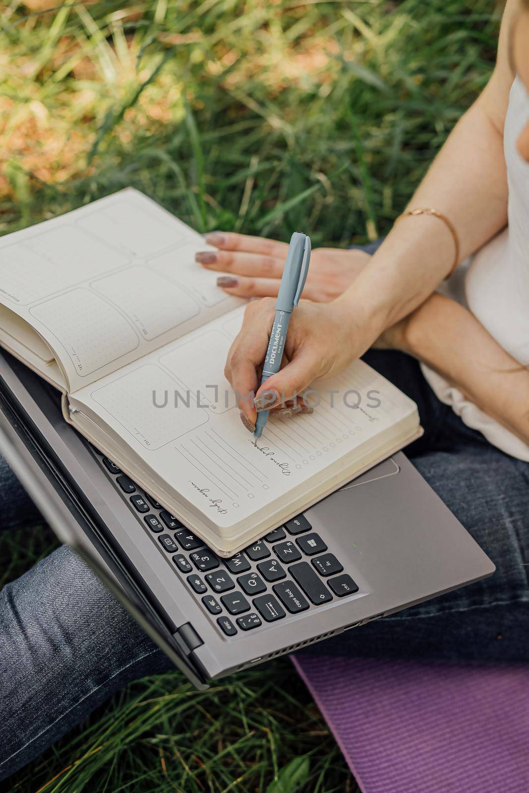 girl sits on the grass and works at a laptop. freelance. selfeducation. the concept of distance learning outdoors