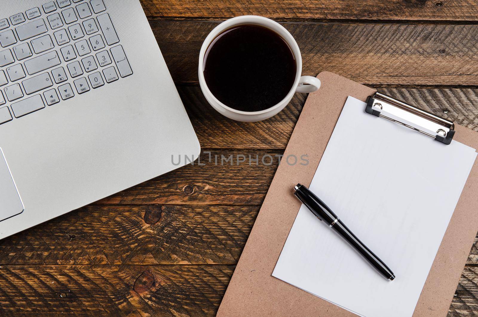 Cup of coffee and laptop on wooden table. Stock image.