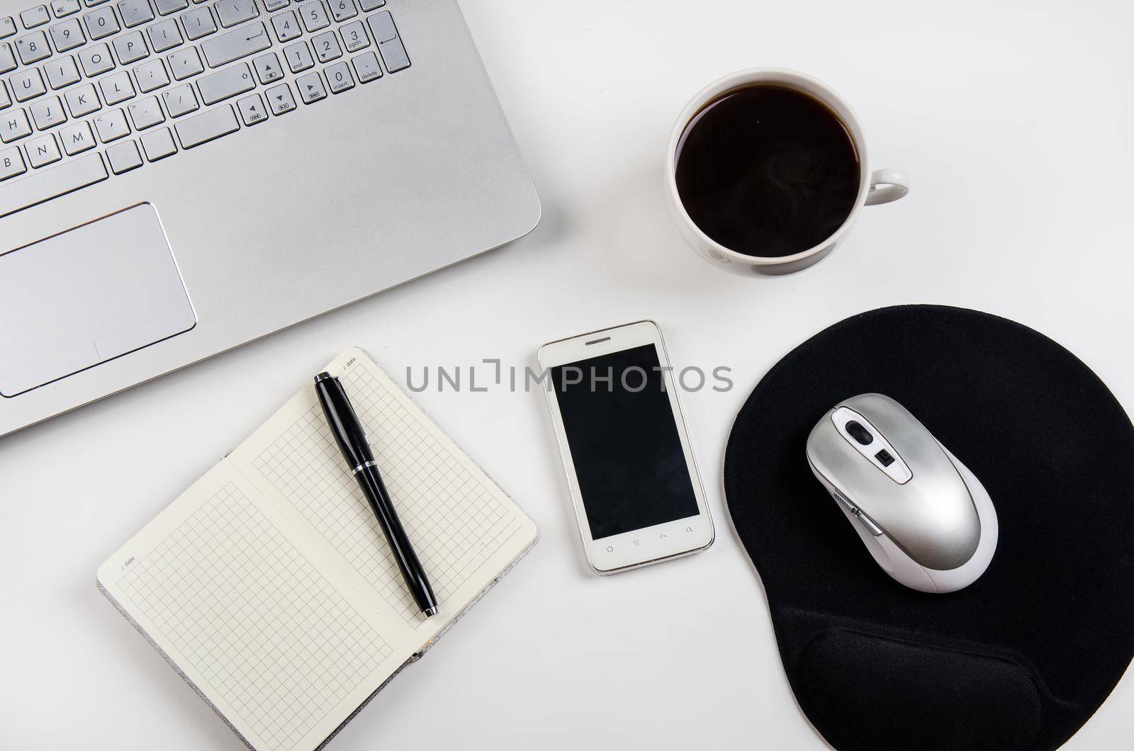 Cup of coffee and laptop on white table. Stock image.