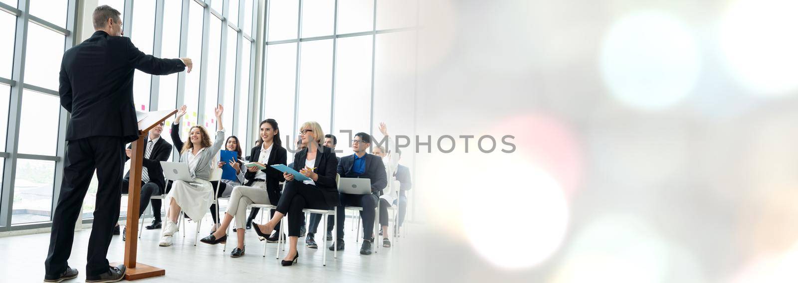 Group of business people meeting in a seminar conference widen view . Audience listening to instructor in employee education training session . Office worker community summit forum with speaker .