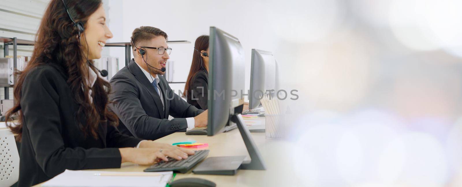 Business people wearing headset working in office to support remote customer or colleague. Call center, telemarketing, customer support agent provide service in broaden view .