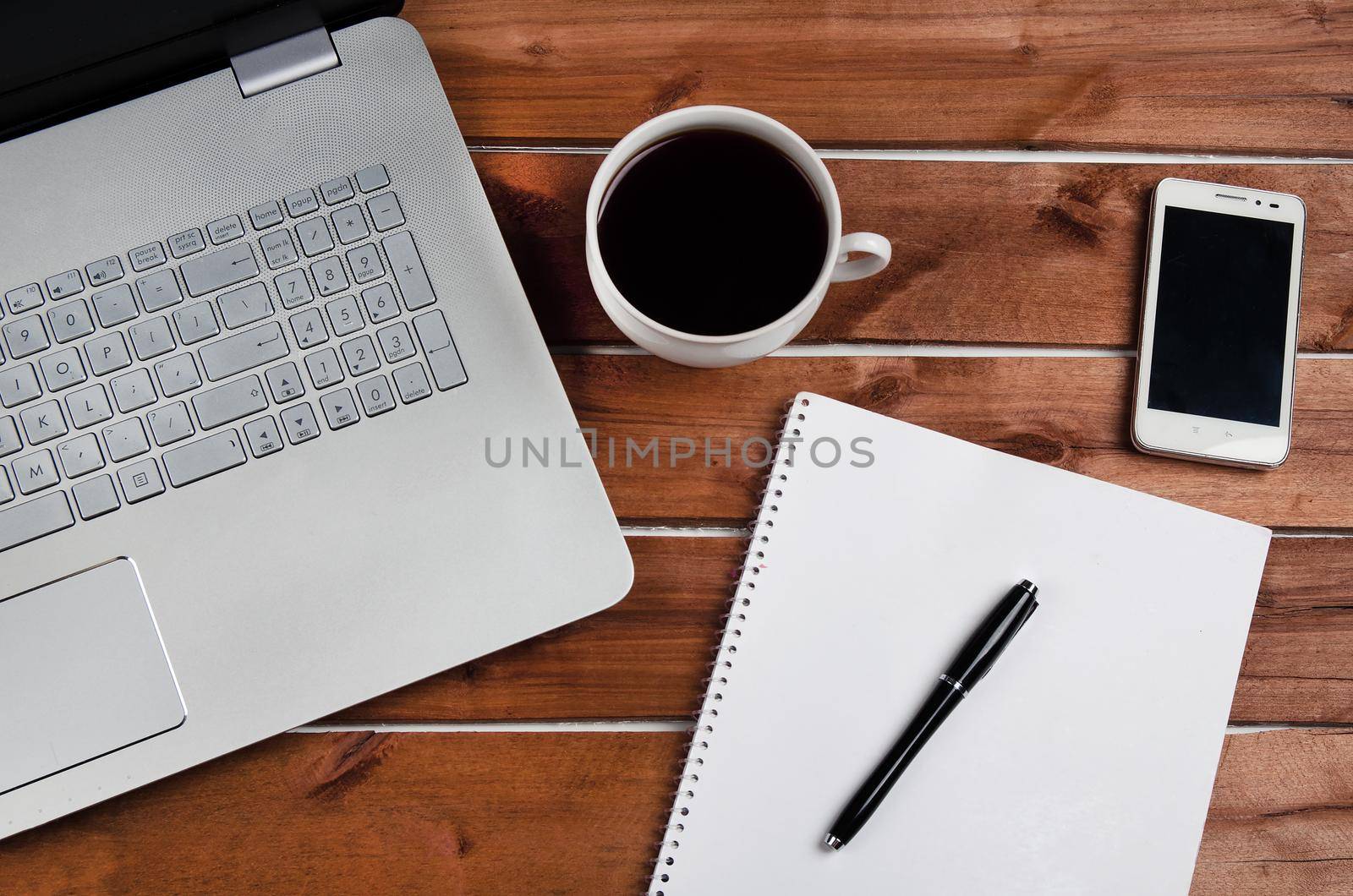 Cup of coffee and laptop on wooden table. Stock image.