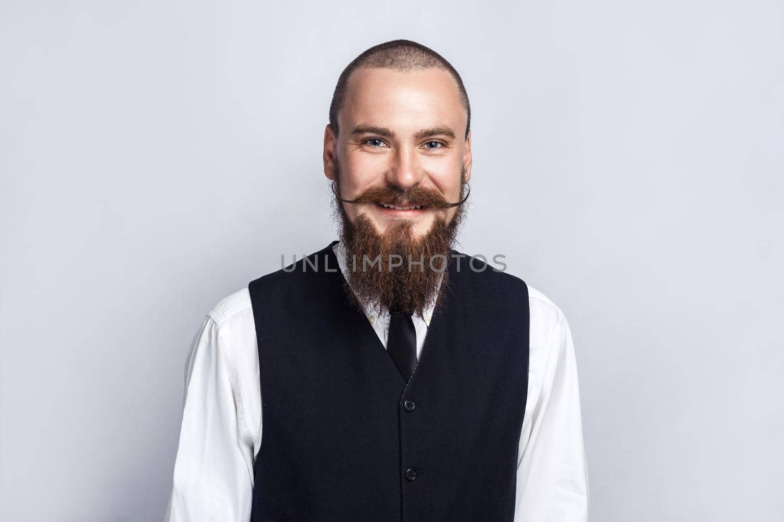 Happiness. Handsome businessman with beard and handlebar mustache looking at camera with toothy smiley face. studio shot, on gray background.