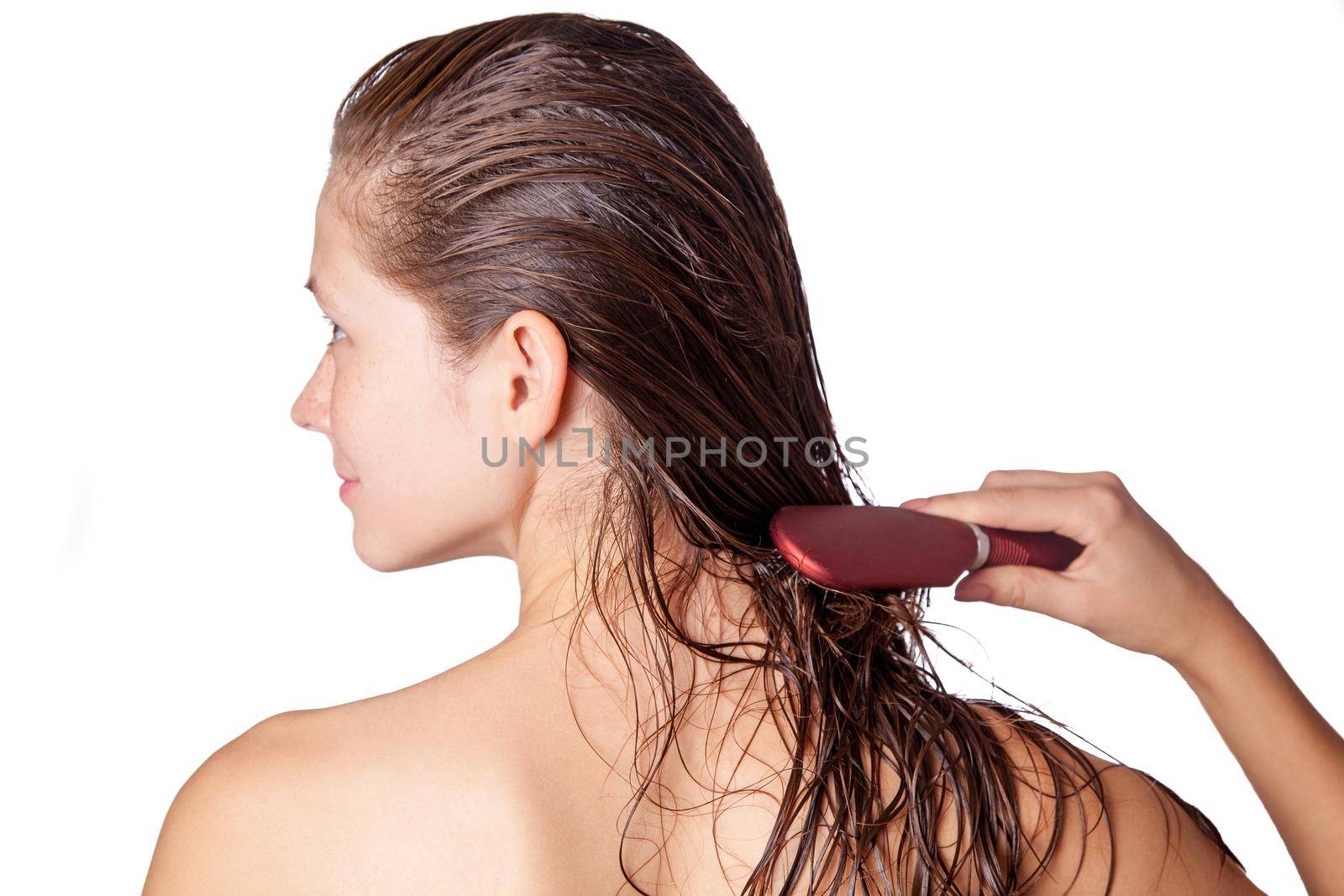 Young beautiful woman with white towel and freckles combing her brown wet hair after showering. studio shot. isolated on white background.