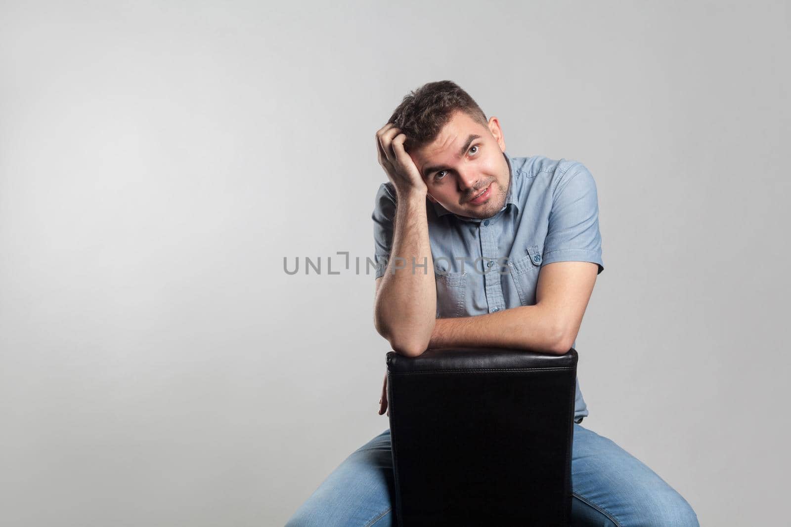 Attractive man sit touching head and thinking. Actors portfolio picture, emotion and feelings. Studio shot, isolated on gray background